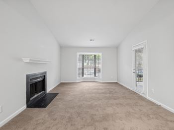 A spacious living room with a fireplace and carpeted floor.